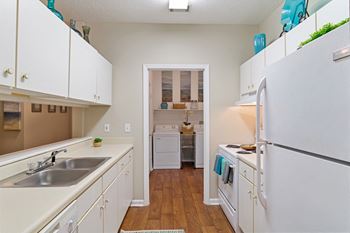 Kitchen with white shaker cabinets, white appliances, and view laundry room in the background